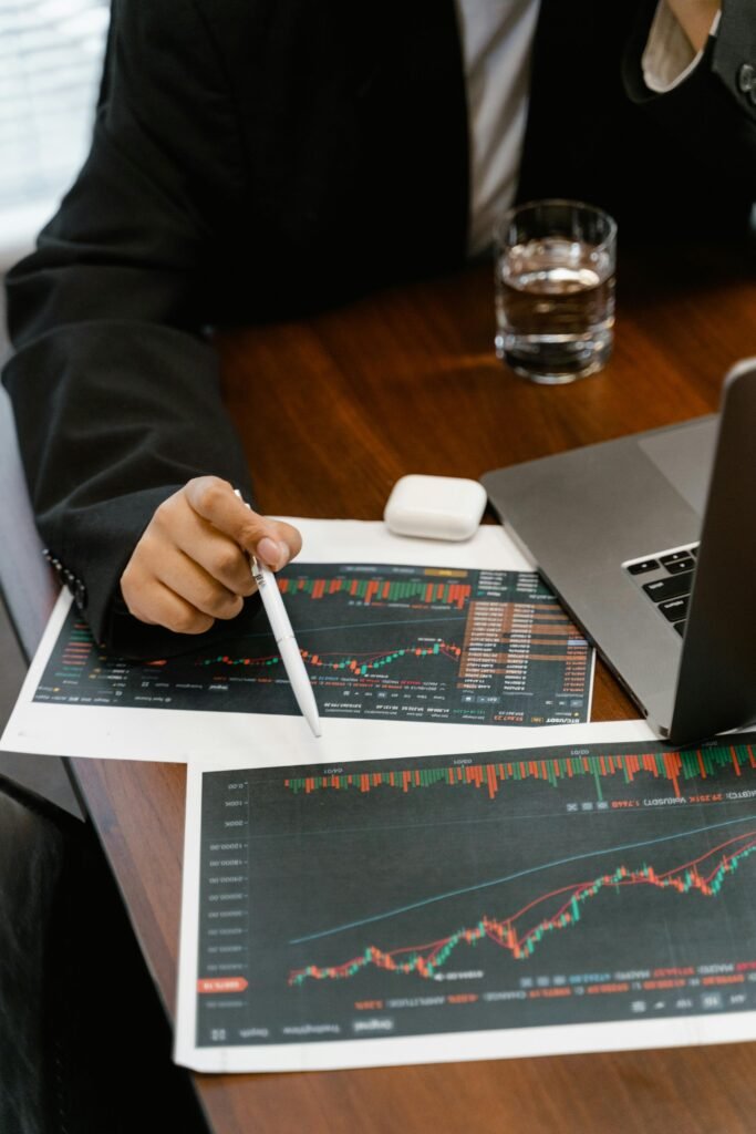 pexels-photo-7567234-7567234 Close-up of a business analyst reviewing printed financial graphs and charts at an office desk.