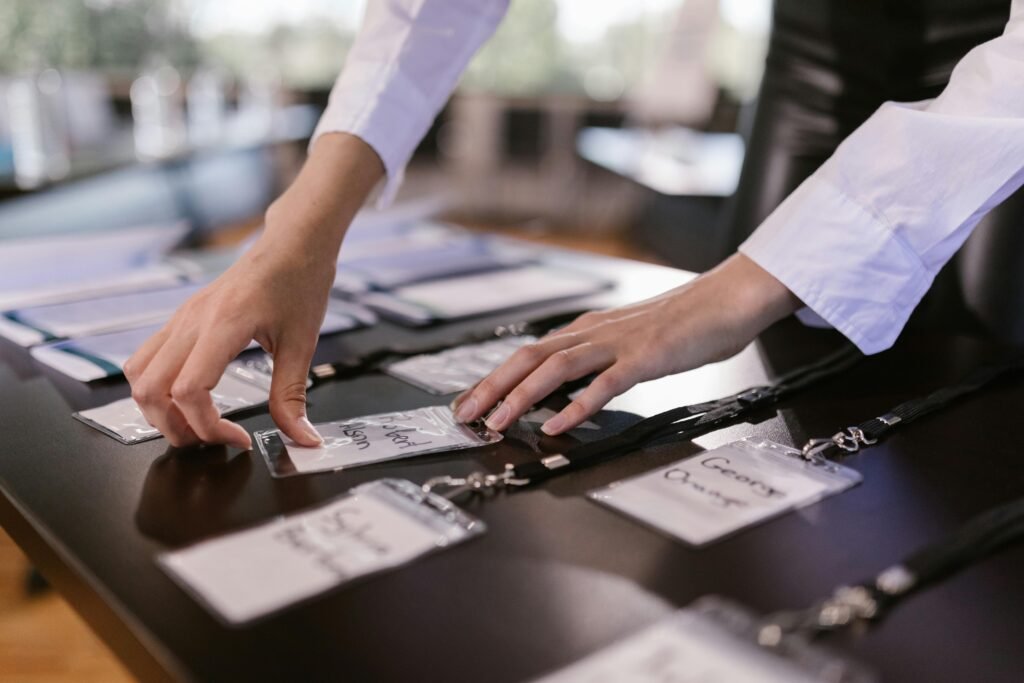 pexels-photo-7648472-7648472 Close-up of hands arranging name tags on a conference table, preparing for a corporate event.