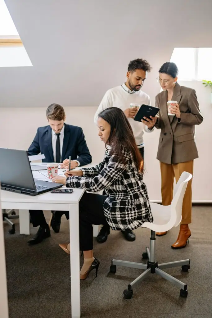 pexels-photo-7693253-7693253 Diverse business team collaborating in an office, working on laptops and discussing projects.